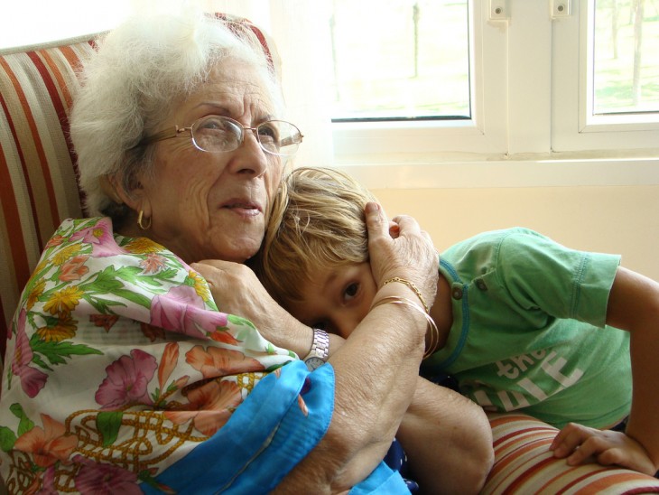 abuelita abrazando a su nieto sentada en un sillón 