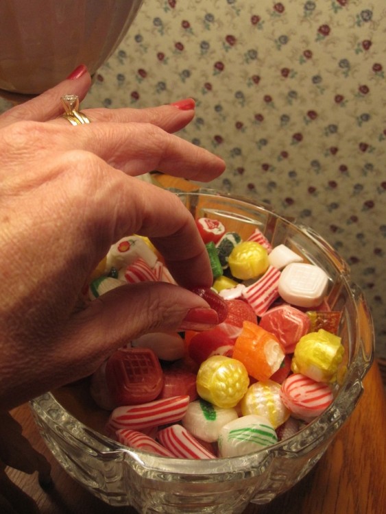 mano de una abuelita agarrando dulces de un recipiente 