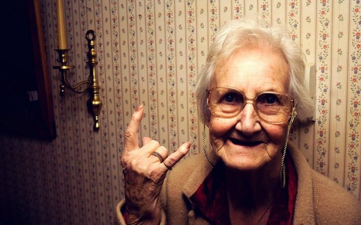 abuelita con la mano levantada haciendo señal de rock and roll 