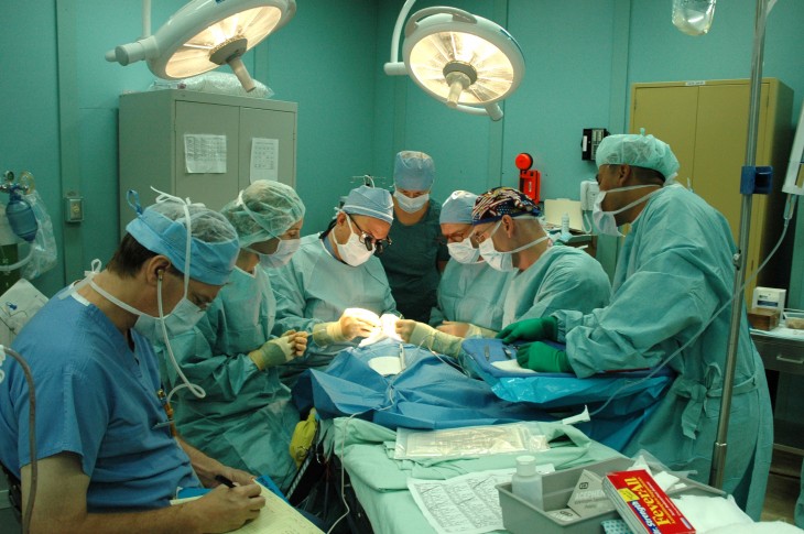ayudantes quirúrgicos y médicos asistiendo a un médico durante una operación 