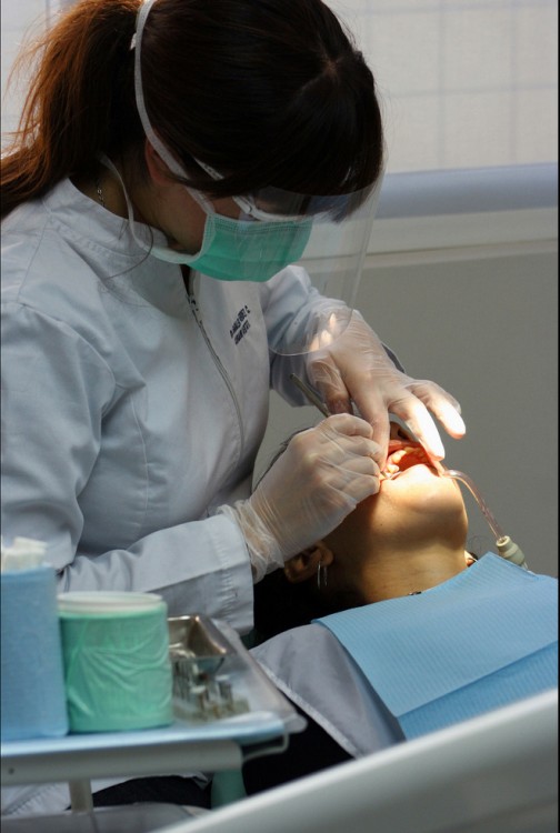 una dentista tratando a una paciente que esta acostada 