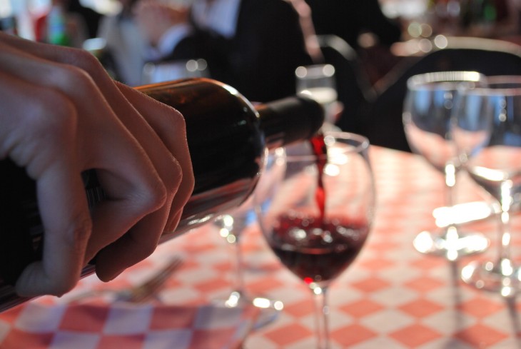 mano de una persona sirviendo una copa de vino tinto 