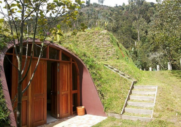 casa con puerta de madera al estilo hobbit rodeada de árboles 