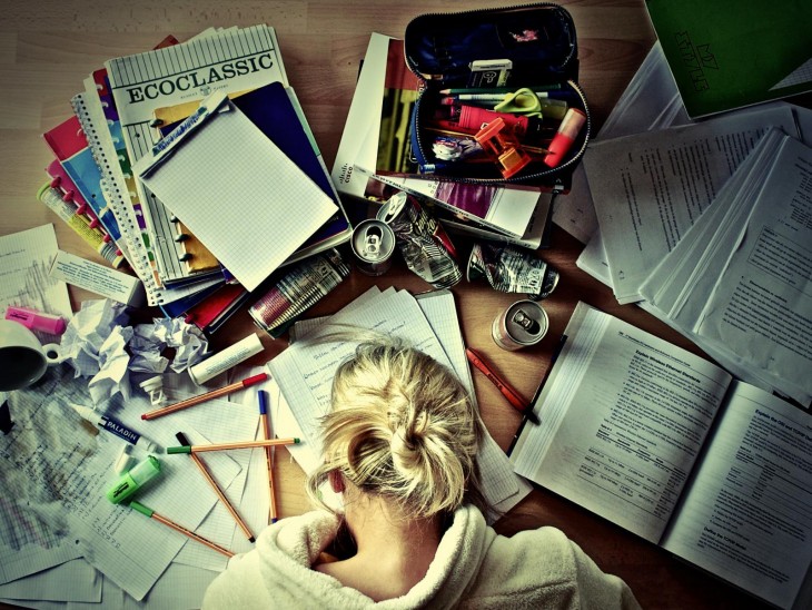 Mujer frente a una mesa llena de libretas y libros 