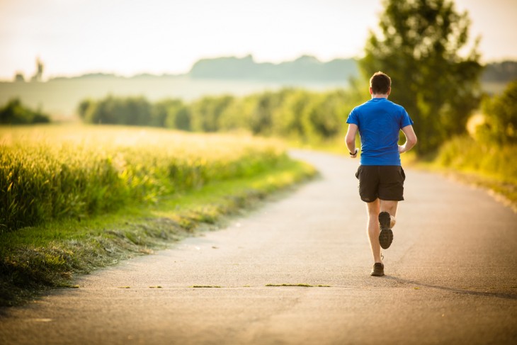 Fotografía de un chico corriendo por una carretera 