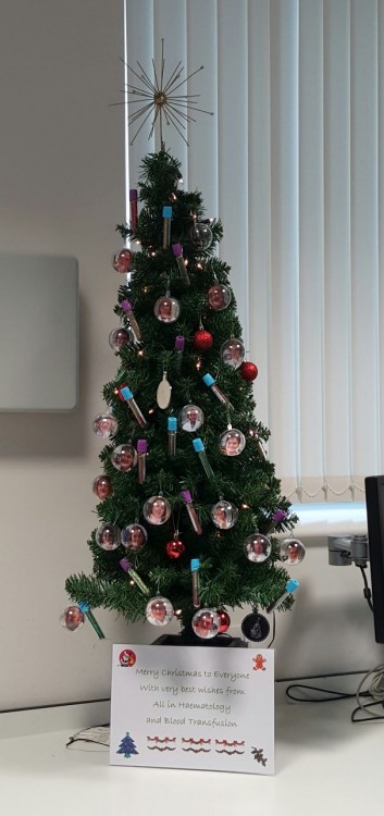 árbol navideño decorado con tubos de hematologia y esferas con fotografías de doctores 