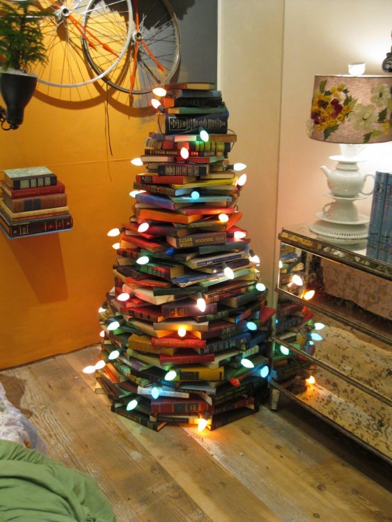 libros apilados formando un árbol de navidad con luces 