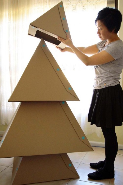 mujer apilando cajas de cartón como árbol de navidad 