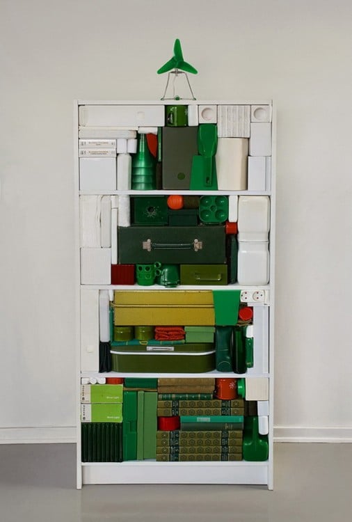 Librero con cosas de colores apiladas en forma de árbol de navidad 