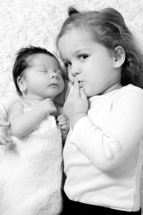 Fotografía de una niña acostada con su hermano bebé 