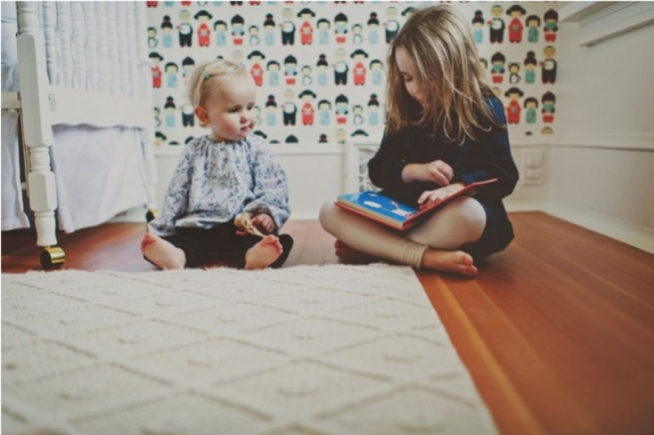 dos niñas sentadas en el suelo viendo un libro 