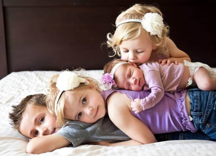 Fotografía de cuatro hermanos uno encima del otro sobre una cama 