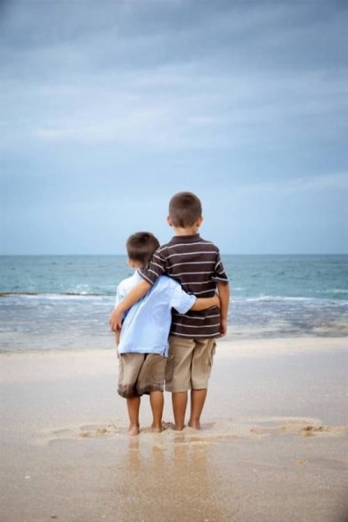 dos niños abrazados frente a la playa 