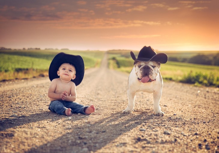 bebé con un sombrero sentado a un lado de su bulldog con sombrero 