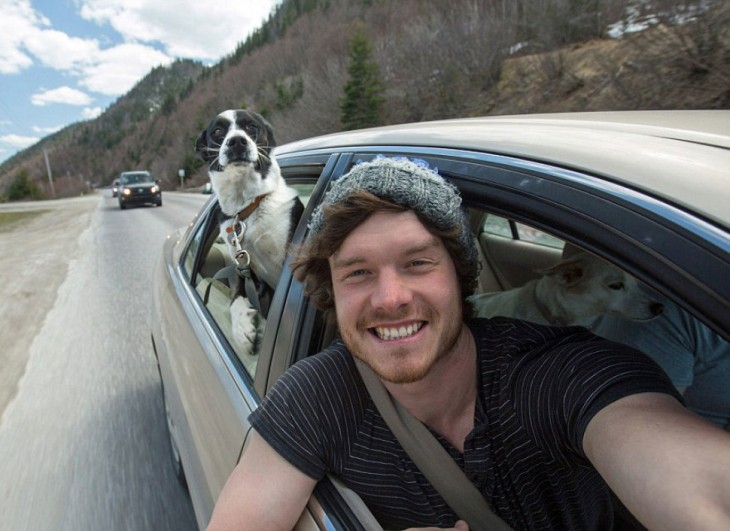 Selfie de un chico dentro de un carro con un perro en la parte trasera 