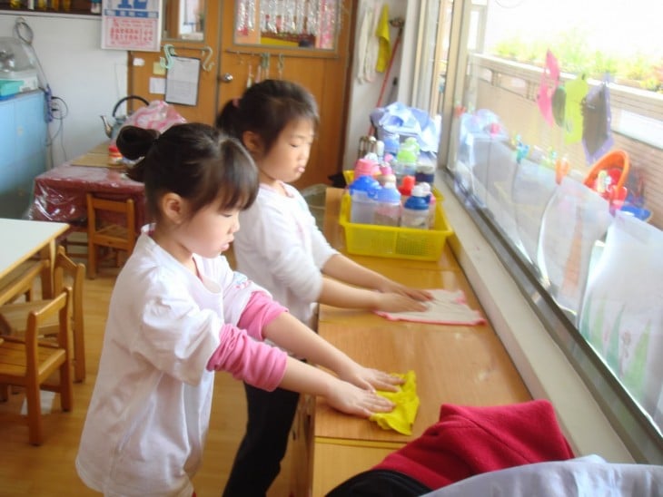 dos niñas japonesas limpiando los muebles de sus aulas 