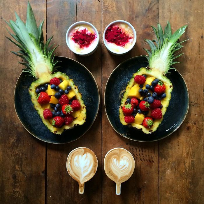 Desayuno simétrico de una piña rellena de fruta con dos tazas de café 