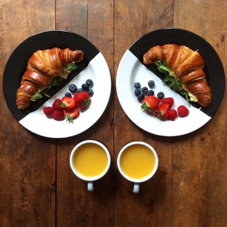 Platillo con cuernitos y frutas rojas simétricas a dos tazas con jugo 