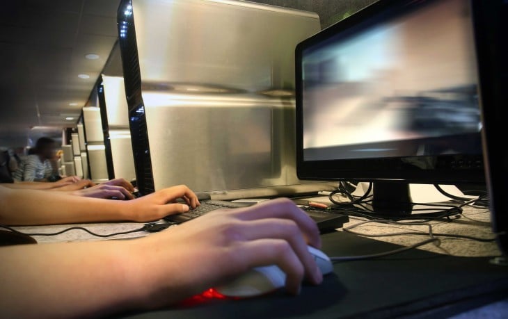 manos de una persona frente a una computadora en un café internet 