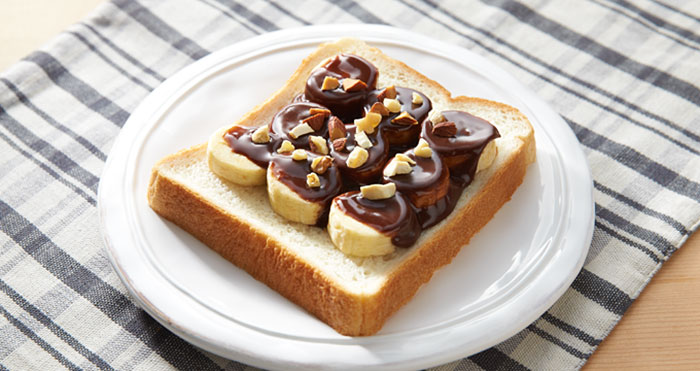 rebanada de pan con oplatano cubierto de chocolate y trozos de cacahuete