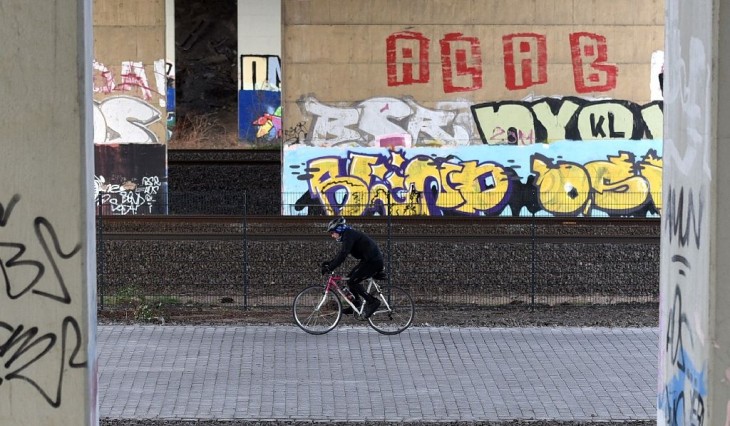 hombre transitando las calles de Alemania sobre su bicicleta cerca de las vías del ferrocarril 