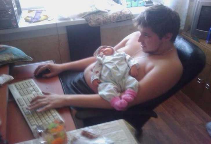 hombre sentado frente a una computadora con su hija sobre su estómago 