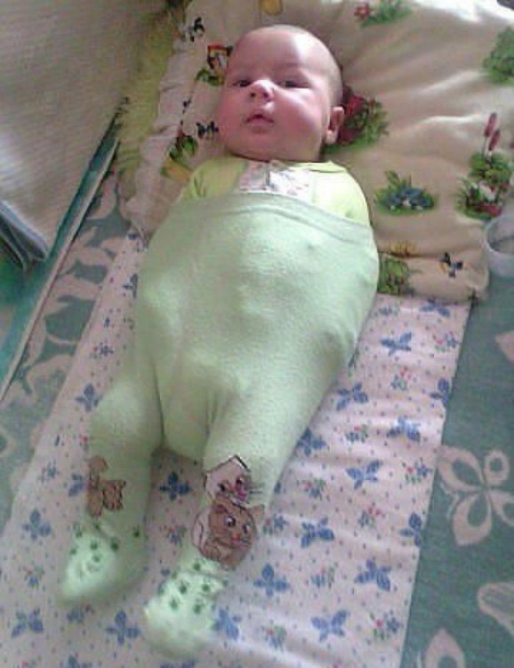 bebé acostado con un pantalón sosteniendo sus brazos 
