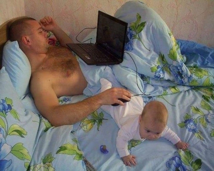 hombre acostado en la computadora usando a su bebé para colocar el ratón 