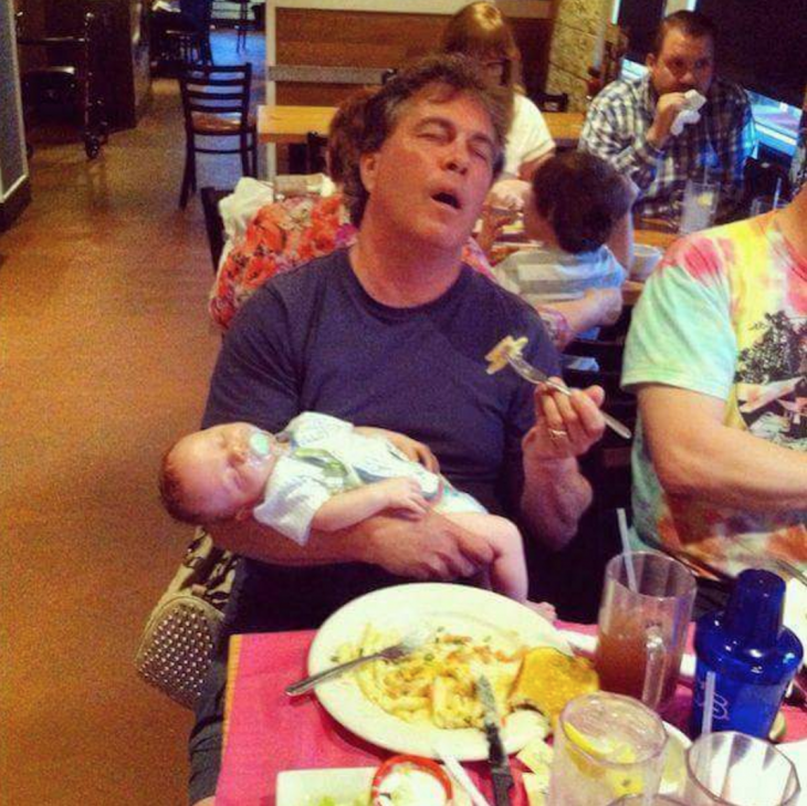 hombre dormido con su hijo en brazos mientras come en un restaurante 