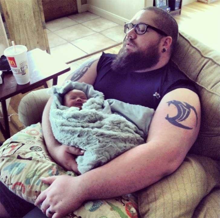 hombre sentado en un sillón dormido con su bebé en brazos 