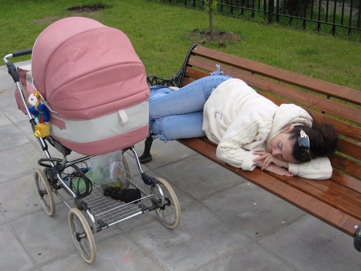 mujer dormida en la banca de un parque a lado de la carreola de su bebé 