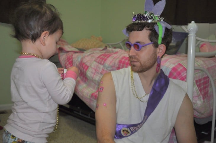 niña adornando a su padre con collares y coronas 