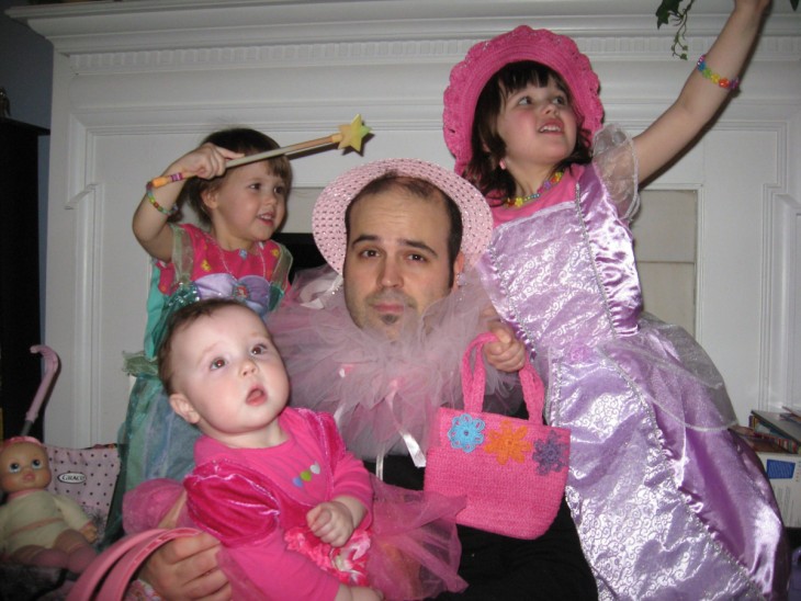 hombre con un sombrero rosa rodeado de sus tres hijas 