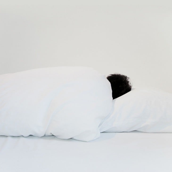 imagen de una persona acostada sobre sábanas blancas 