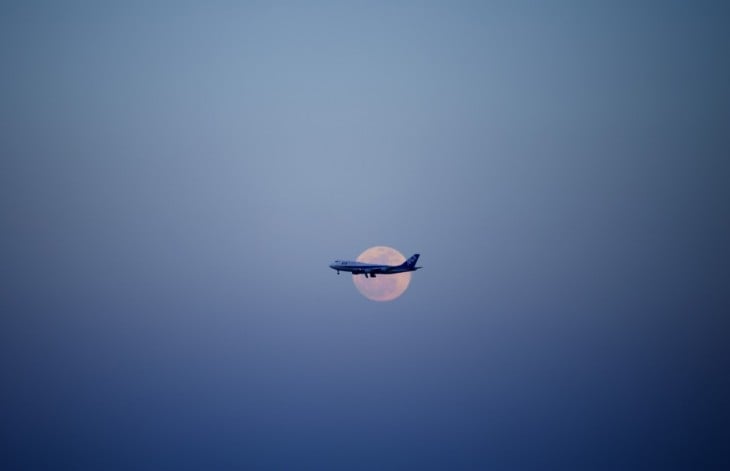 imagen de un avión pasando frente a la luna 