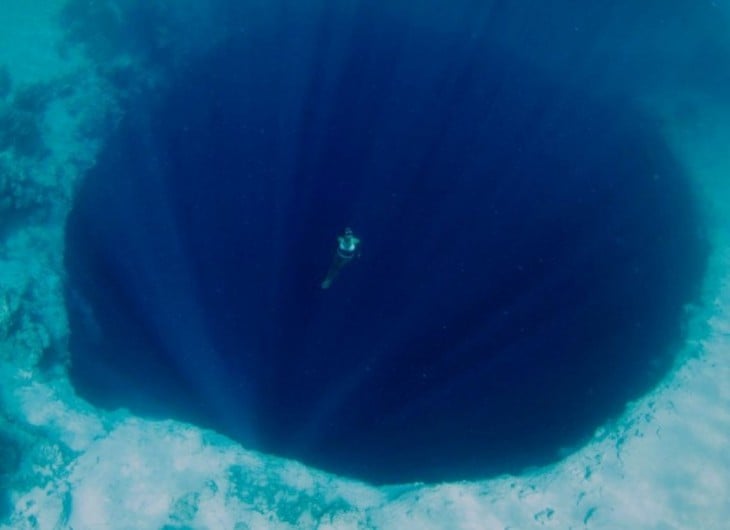 Fotografía de una chica nadando cerca de un profundo abismo 