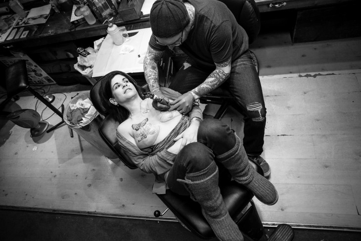 Hombre tatuando los senos de una mujer 