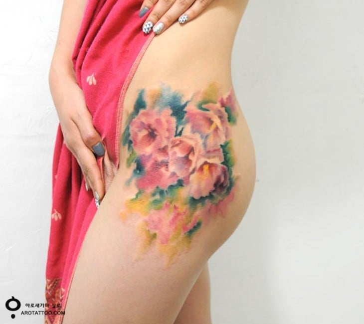 Tatuaje sobre el muslo de una mujer con un diseño floral 