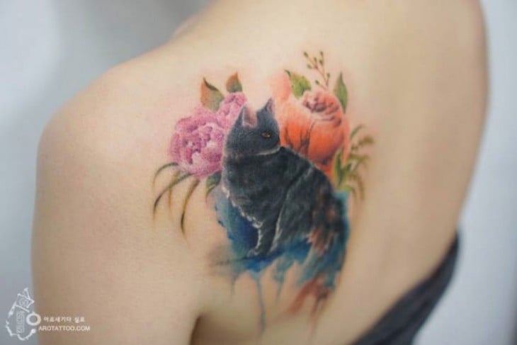 Tatuaje acuarela con el diseño de un gato rodeado de flores 