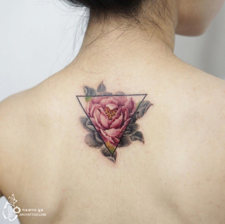 Tatuaje con el diseño de una flor detrás de un triángulo 