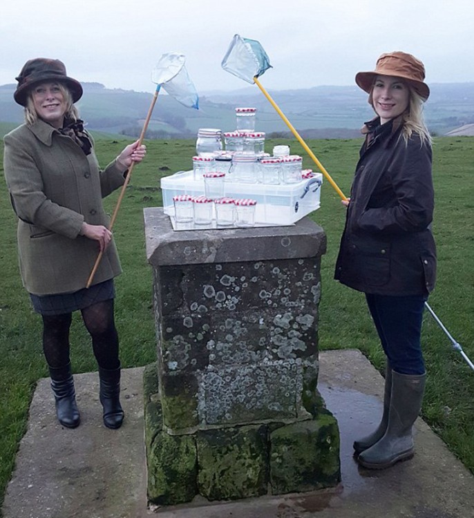 mujeres británicas con redes y muchos frascos de aire fresco apilados sobre una piedra 