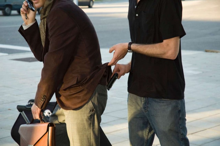 chico sacando la cartera de un hombre que va caminando por la calle 