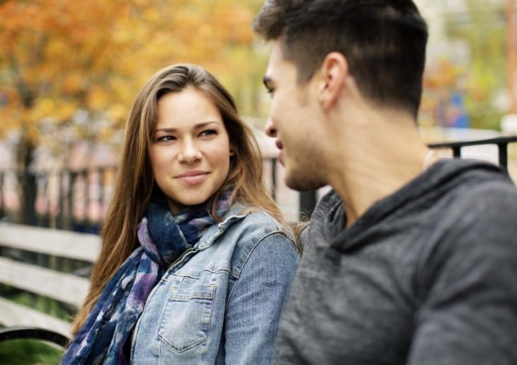 chica mirando fijamente a un chico frente a ella en una banca 