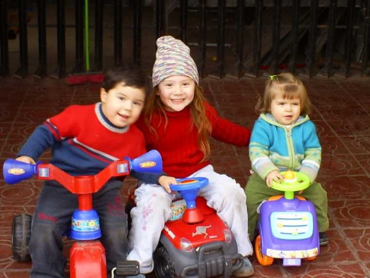 fotografía de tres niños en carritos jugando en la calle 