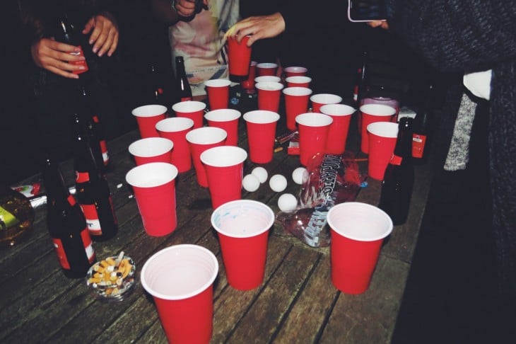mesa de centro llena de botellas de cerveza y vasos rojos 