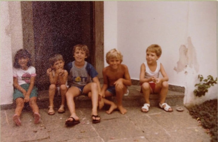fotografía vieja de cinco niños sentados afuera de una casa 