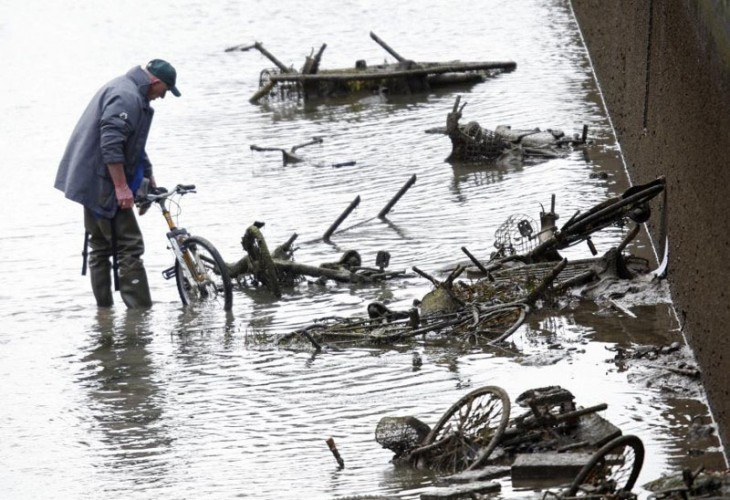 Hombre en París checando muchas bicicletas hundidas en el canal de Saint-Martin en París 