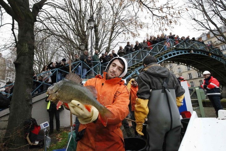 servidor público en París con un enorme pez en sus manos 