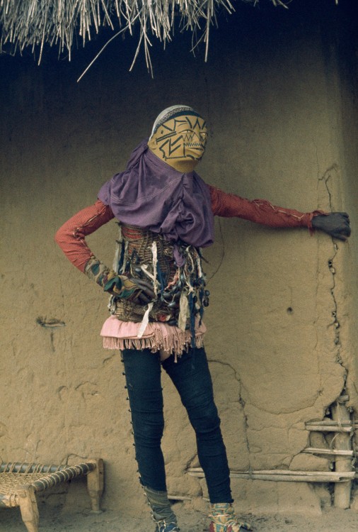 Personifying evil, a costumed mapico dancer in Mozambique hides from spectators, 1964.