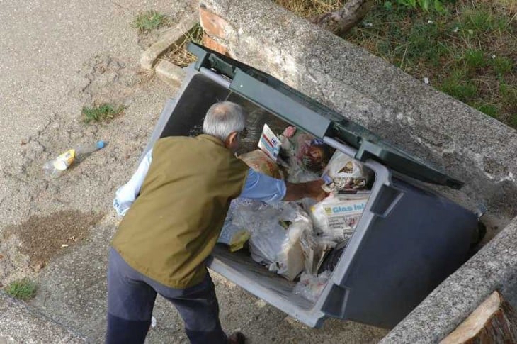 HOMBRE BUSCANDO ENTRE LA BASURA COMIDA LIMPIA Y COMESTIBLE PARA SUBSISTIR EN FRANCIA